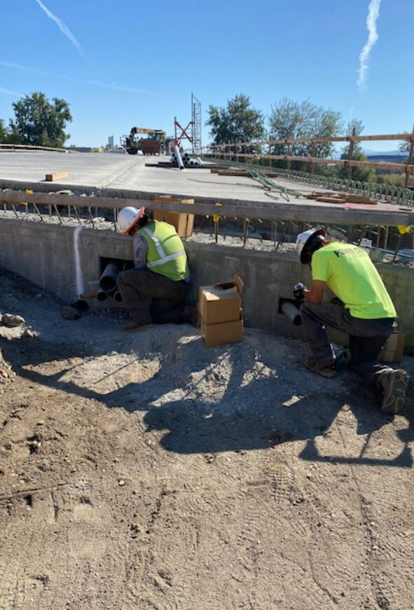 Two men working on site with hardhats on.