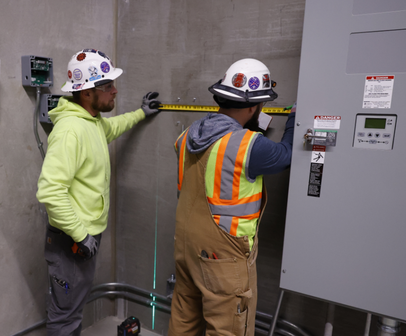 Two men inspecting an Electrical Panel.